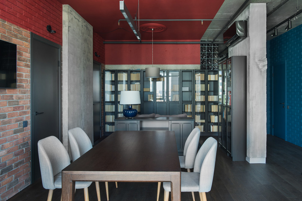 Стильный дизайн: рабочее место среднего размера в стиле лофт с красными стенами, темным паркетным полом, отдельно стоящим рабочим столом, коричневым полом и кирпичными стенами без камина - последний тренд