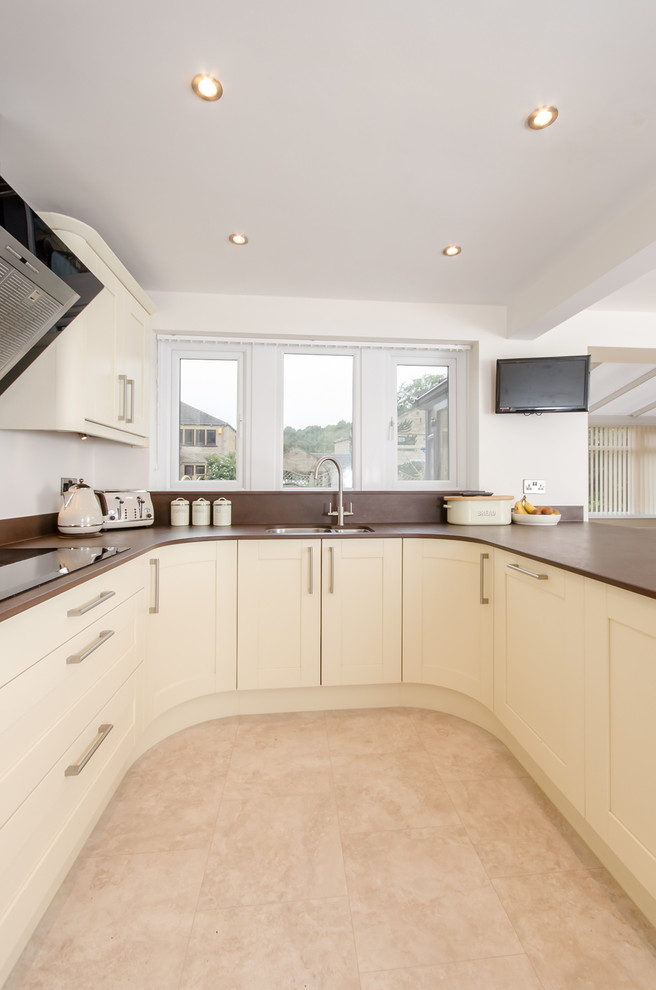 This is an example of a mid-sized contemporary u-shaped kitchen in Other with an undermount sink, solid surface benchtops, brown splashback and stainless steel appliances.