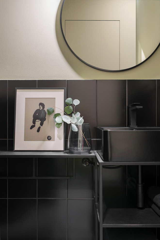 Idée de décoration pour un petit WC et toilettes design avec des portes de placard noires, un carrelage vert, un mur vert, un sol gris, un plan de toilette noir et meuble-lavabo sur pied.