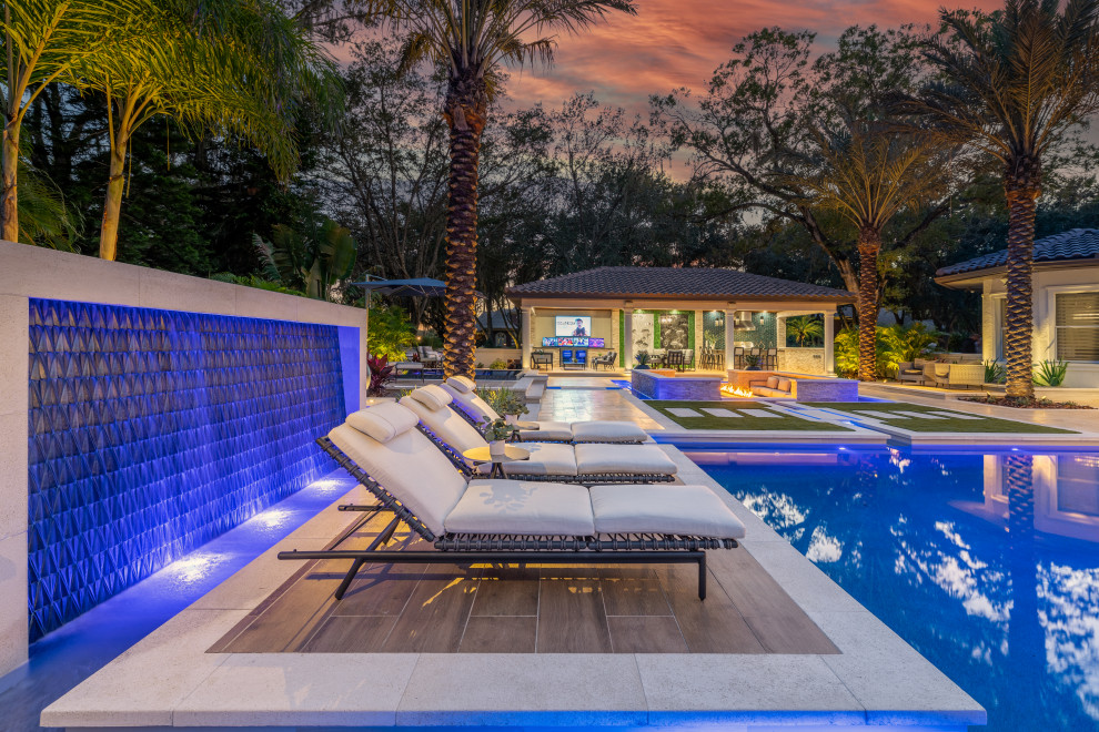 Foto de piscina infinita contemporánea extra grande a medida en patio trasero con paisajismo de piscina y suelo de baldosas