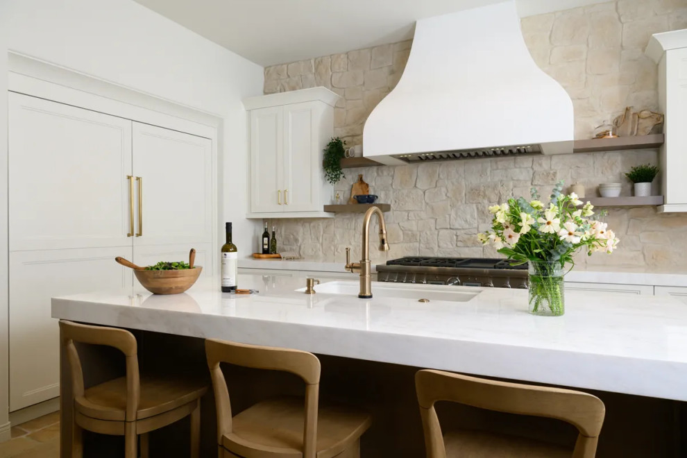 Inspiration for a transitional u-shaped travertine floor and beige floor eat-in kitchen remodel in Orange County with a farmhouse sink, shaker cabinets, white cabinets, quartz countertops, multicolored backsplash, stone tile backsplash, stainless steel appliances, an island and white countertops