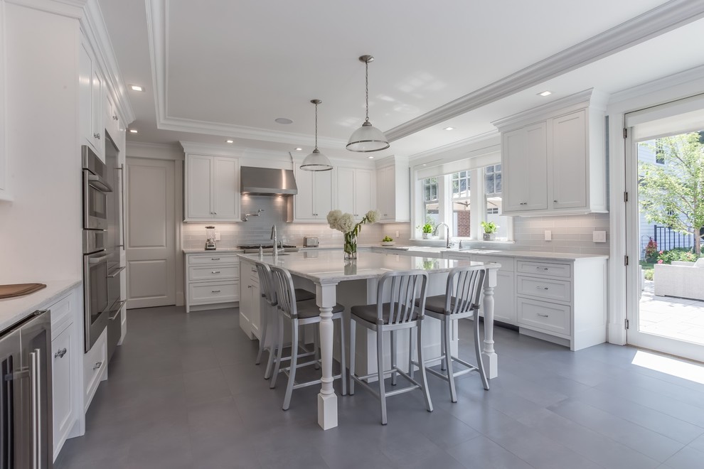 Photo of a large transitional l-shaped kitchen pantry in New York with an undermount sink, recessed-panel cabinets, white cabinets, solid surface benchtops, white splashback, stone tile splashback, stainless steel appliances, medium hardwood floors, with island and brown floor.