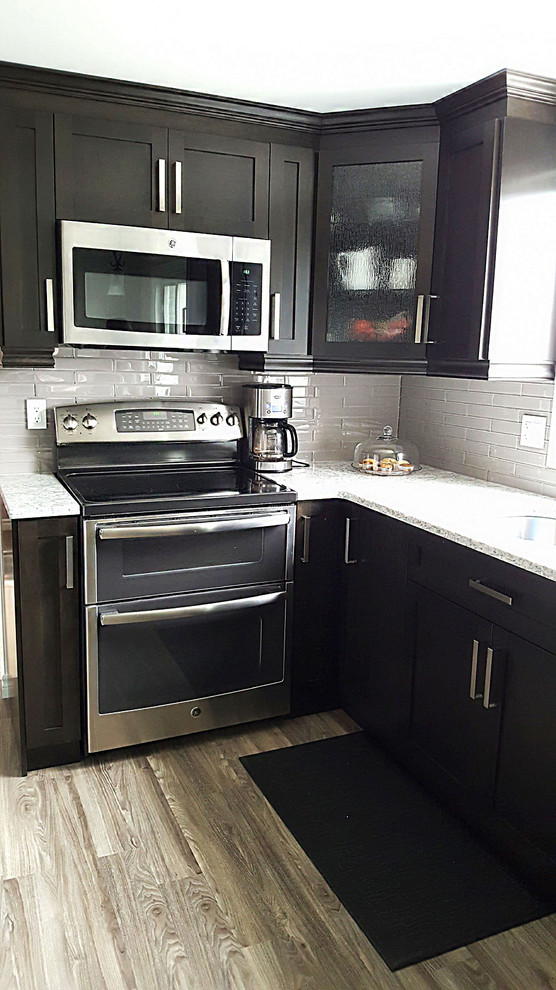 Inspiration for a large transitional l-shaped eat-in kitchen remodel in Toronto with an undermount sink, recessed-panel cabinets, dark wood cabinets, quartzite countertops, beige backsplash, glass tile backsplash and white countertops