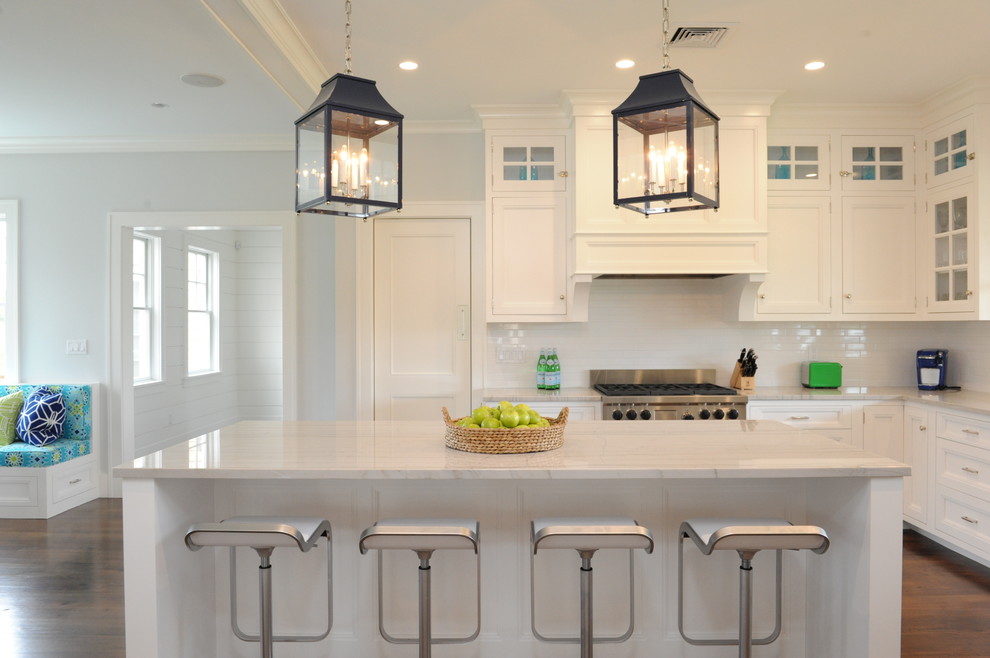This is an example of a beach style kitchen in Boston with recessed-panel cabinets, white cabinets, white splashback, subway tile splashback, stainless steel appliances, dark hardwood floors and with island.