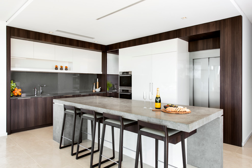 Expansive contemporary galley eat-in kitchen in Perth with an undermount sink, flat-panel cabinets, white cabinets, marble benchtops, beige splashback, stone slab splashback, white appliances, limestone floors and with island.