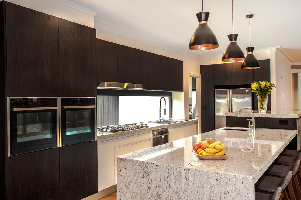 Design ideas for a large contemporary galley open plan kitchen in Melbourne with a double-bowl sink, flat-panel cabinets, dark wood cabinets, granite benchtops, window splashback, stainless steel appliances, medium hardwood floors, with island, brown floor and multi-coloured benchtop.
