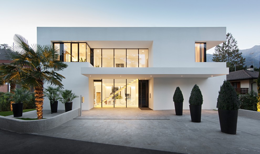 Design ideas for a large contemporary two-storey stucco white exterior in Other with a flat roof.