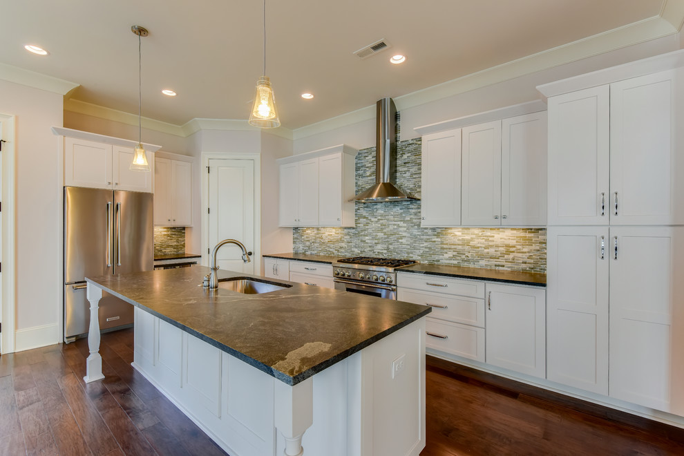 Inspiration for a mid-sized transitional l-shaped medium tone wood floor eat-in kitchen remodel in Charlotte with a drop-in sink, recessed-panel cabinets, white cabinets, quartzite countertops, gray backsplash, glass tile backsplash, stainless steel appliances and an island