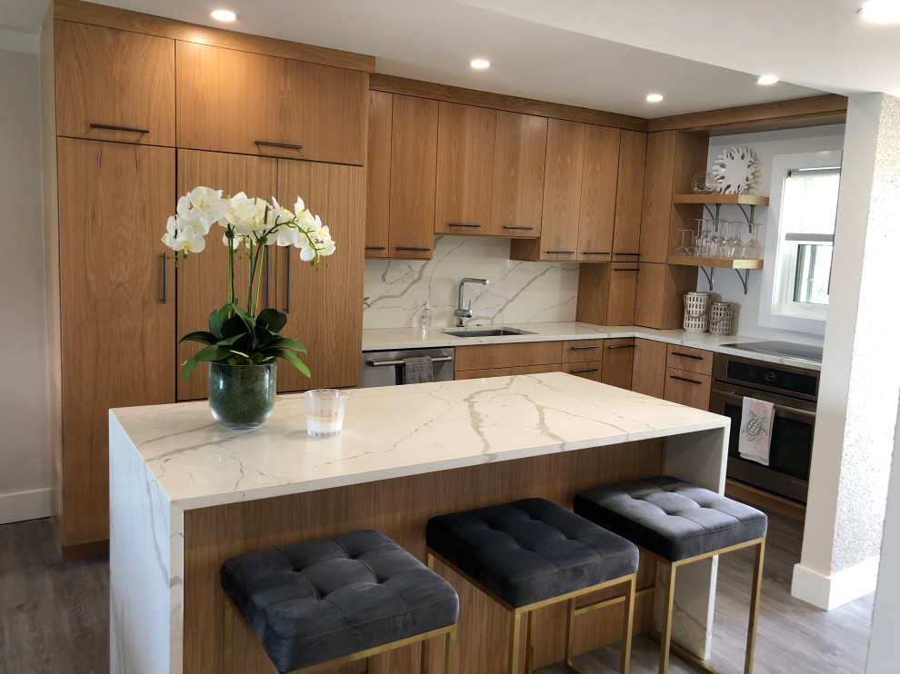 Photo of a small beach style l-shaped kitchen in Miami with an undermount sink, flat-panel cabinets, medium wood cabinets, quartz benchtops, white splashback, engineered quartz splashback, stainless steel appliances, vinyl floors, with island, grey floor and white benchtop.