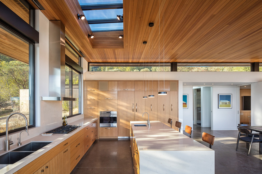 Large modern eat-in kitchen in San Francisco with flat-panel cabinets, light wood cabinets, concrete benchtops, stainless steel appliances, concrete floors, with island and a double-bowl sink.