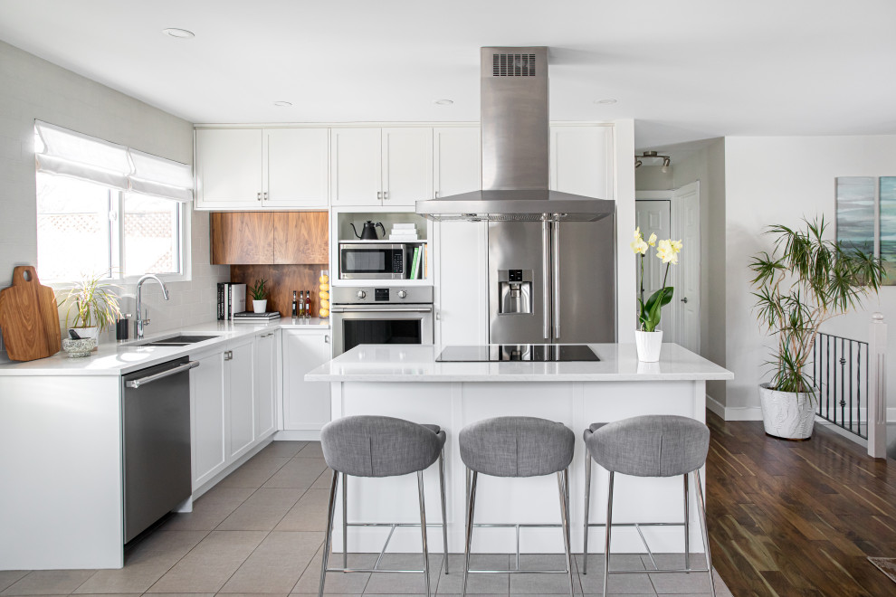 Example of a mid-sized transitional l-shaped porcelain tile and gray floor eat-in kitchen design in Calgary with a double-bowl sink, shaker cabinets, white cabinets, quartzite countertops, white backsplash, porcelain backsplash, stainless steel appliances, an island and white countertops