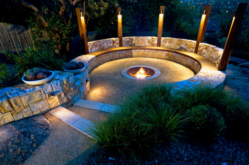 Photo of an australian native transitional backyard full sun garden for winter in Sydney with a fire feature and natural stone pavers.