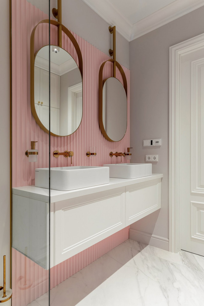 Идея дизайна: большая детская, серо-белая ванная комната в современном стиле с фасадами с выступающей филенкой, белыми фасадами, ванной в нише, инсталляцией, розовой плиткой, серыми стенами, полом из керамогранита, накладной раковиной, столешницей из искусственного камня, серым полом, душем с распашными дверями, белой столешницей, зеркалом с подсветкой, тумбой под две раковины, подвесной тумбой, многоуровневым потолком и панелями на части стены