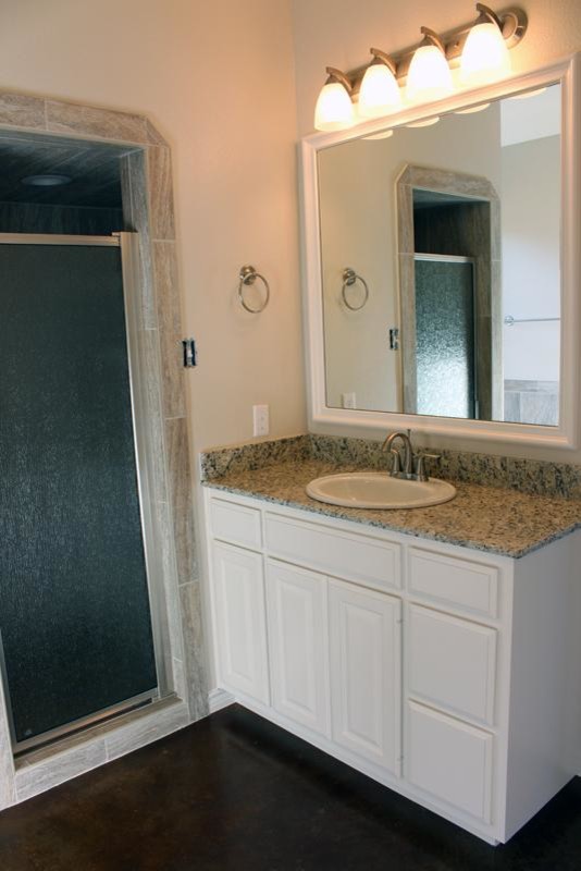 Example of a transitional master beige tile and stone tile concrete floor alcove shower design in Austin with raised-panel cabinets, white cabinets, a two-piece toilet, beige walls, a drop-in sink and granite countertops