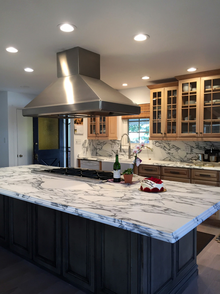 Inspiration for a mid-sized traditional l-shaped eat-in kitchen in Sacramento with a farmhouse sink, glass-front cabinets, light wood cabinets, marble benchtops, multi-coloured splashback, stone slab splashback, stainless steel appliances, light hardwood floors and with island.