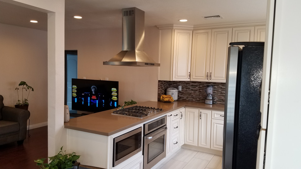 Photo of a mid-sized contemporary u-shaped eat-in kitchen in Los Angeles with an undermount sink, shaker cabinets, beige cabinets, quartzite benchtops, brown splashback, glass tile splashback, stainless steel appliances, terra-cotta floors, no island, beige floor and brown benchtop.