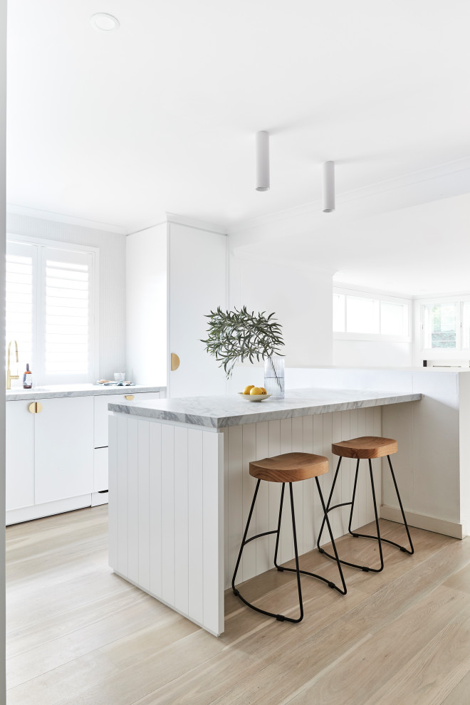 Inspiration for a mid-sized scandinavian u-shaped kitchen in Sydney with a double-bowl sink, shaker cabinets, white cabinets, marble benchtops, white splashback, marble splashback, panelled appliances, light hardwood floors, with island, beige floor, grey benchtop and coffered.