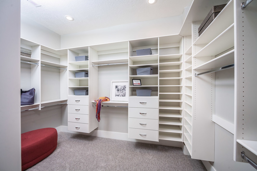 Design ideas for a mid-sized gender-neutral walk-in wardrobe in Salt Lake City with white cabinets, carpet and brown floor.