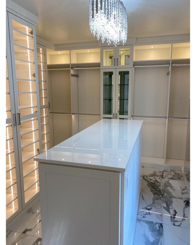 Photo of a modern storage and wardrobe in Los Angeles with shaker cabinets, white cabinets, marble floors and white floor.