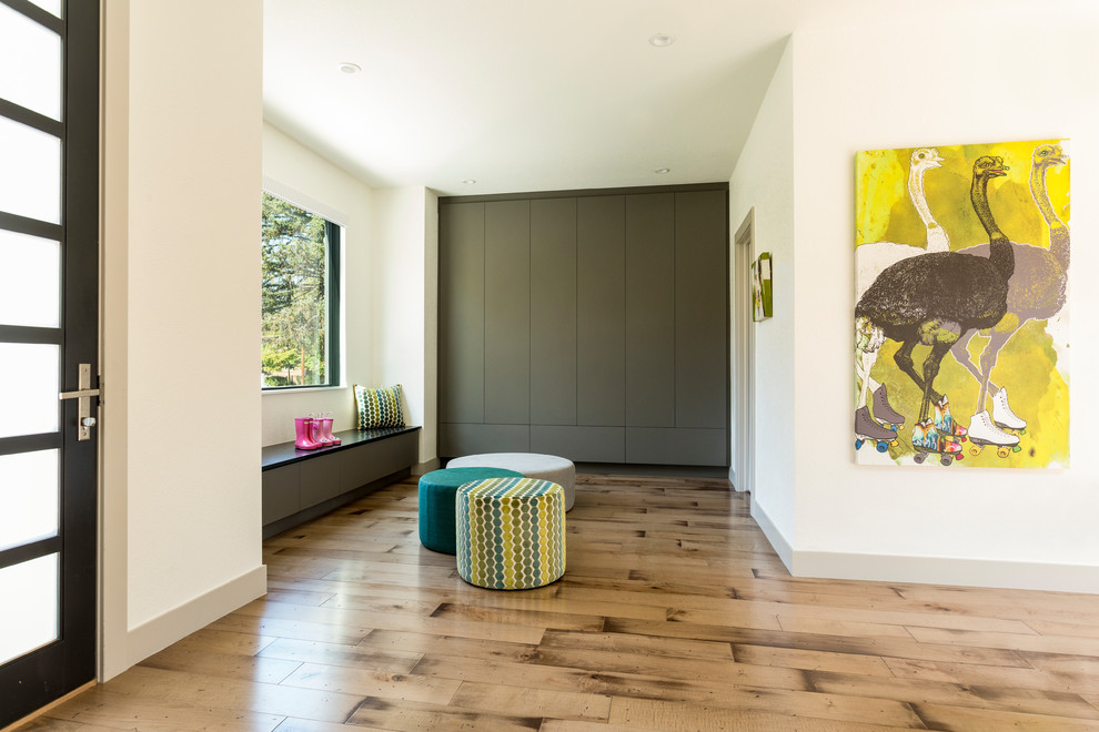Inspiration for a large contemporary mudroom in Denver with white walls, a single front door and light hardwood floors.