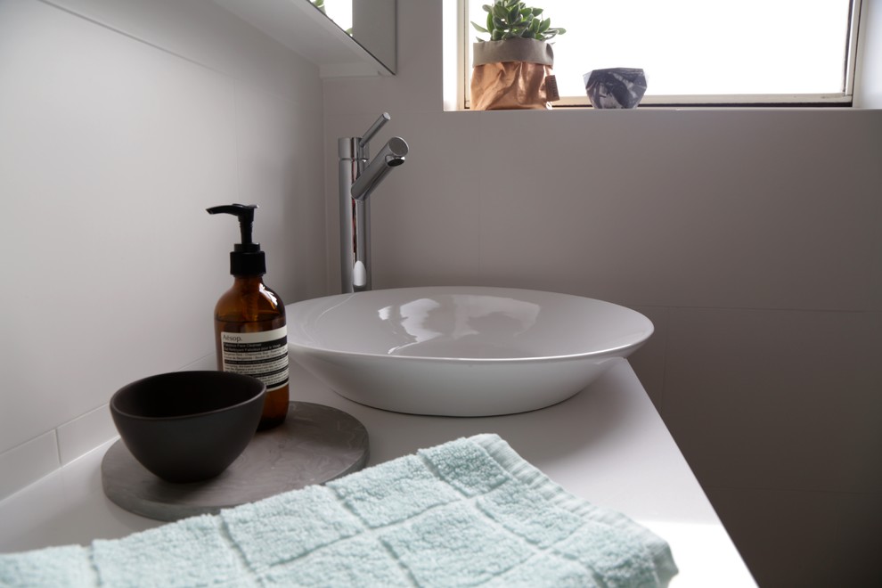 Design ideas for a small scandinavian 3/4 bathroom in Sydney with furniture-like cabinets, light wood cabinets, a drop-in tub, a shower/bathtub combo, a one-piece toilet, gray tile, ceramic tile, white walls, ceramic floors, a console sink and engineered quartz benchtops.