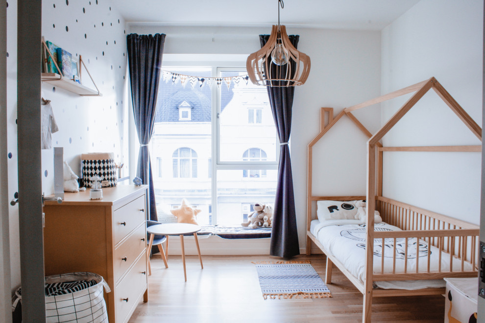 Modelo de dormitorio infantil de 1 a 3 años y blanco escandinavo con paredes blancas, suelo de madera en tonos medios y suelo marrón