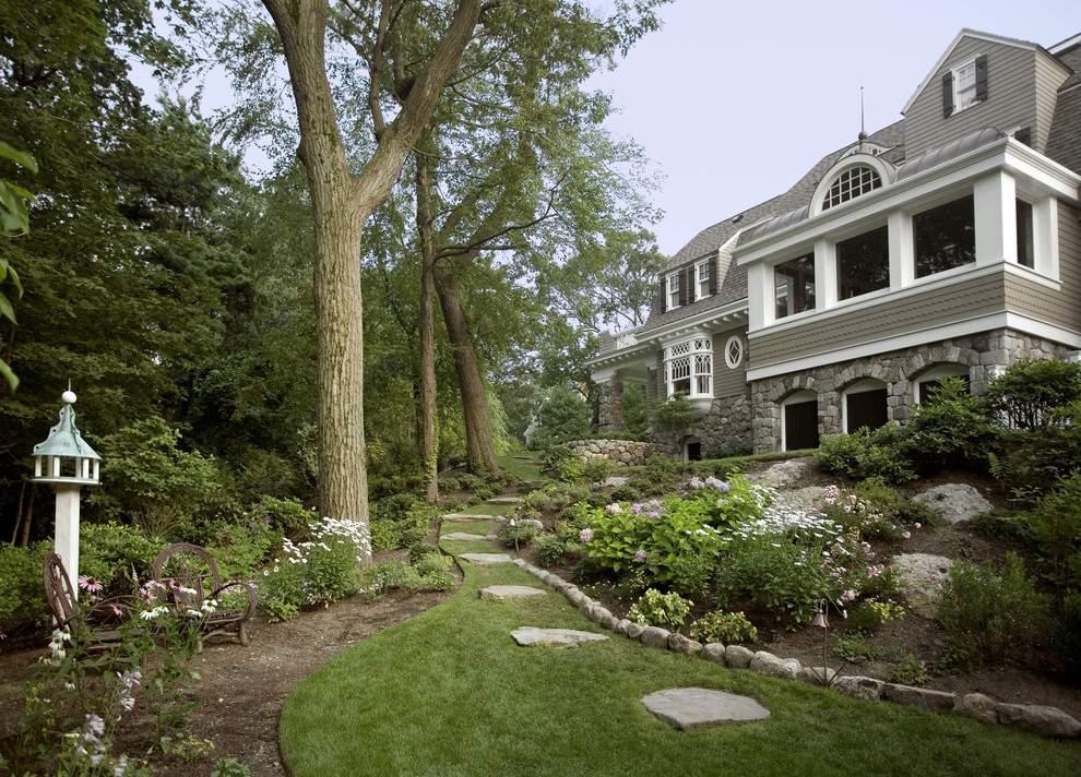 This is an example of an expansive traditional sloped partial sun garden in Boston with natural stone pavers.