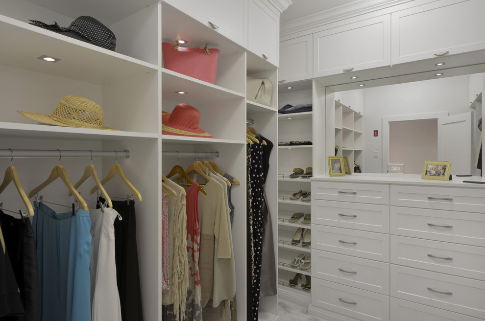 This is an example of a large contemporary gender-neutral walk-in wardrobe in New York with shaker cabinets, white cabinets and carpet.