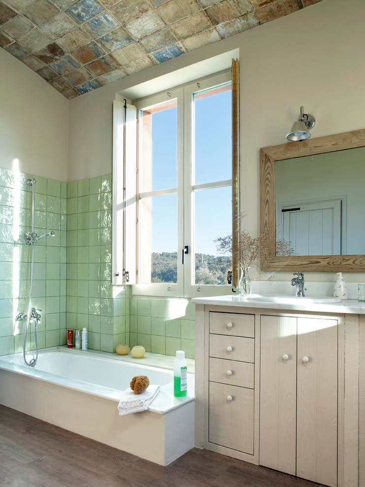 Mid-sized mediterranean master bathroom in Other with flat-panel cabinets, light wood cabinets, a drop-in tub, a shower/bathtub combo, ceramic tile, beige walls, medium hardwood floors, an undermount sink and green tile.