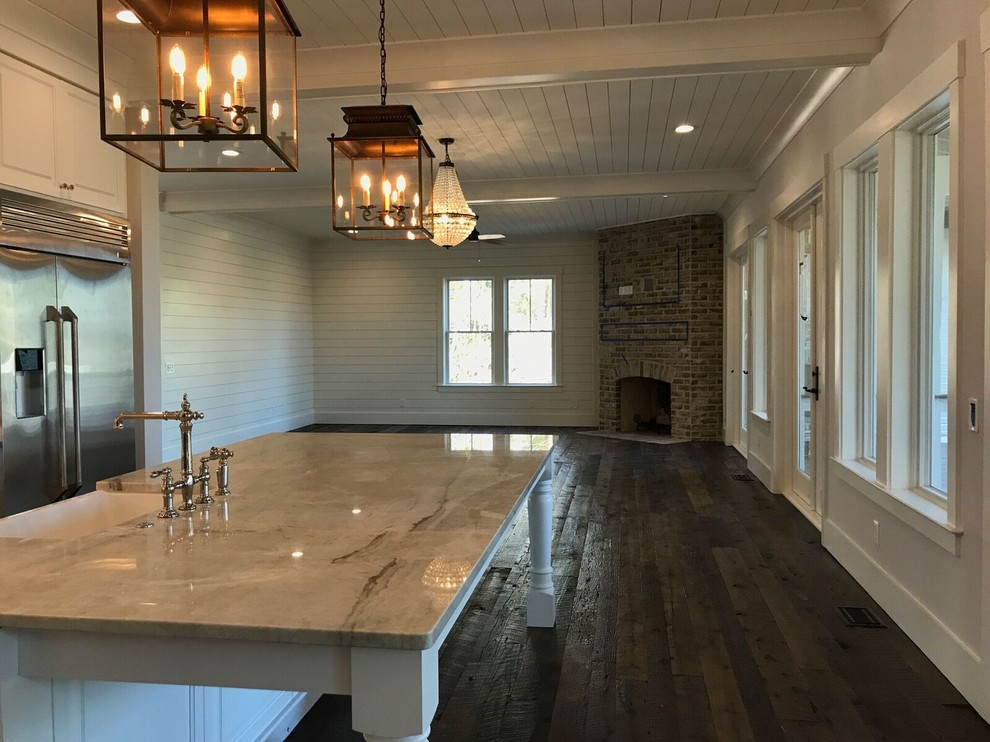 Mid-sized country l-shaped open plan kitchen in Charleston with a farmhouse sink, raised-panel cabinets, white cabinets, marble benchtops, brown splashback, brick splashback, stainless steel appliances, dark hardwood floors, with island and brown floor.