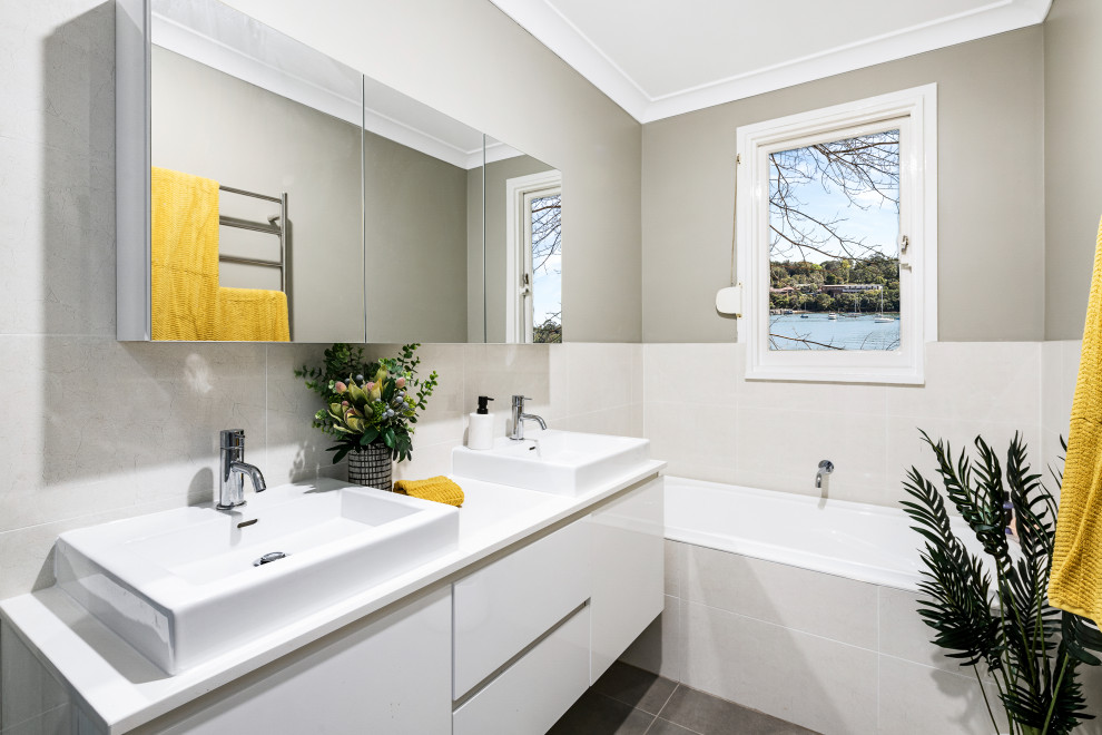 Photo of a contemporary bathroom in Sydney with flat-panel cabinets, white cabinets, an alcove tub, gray tile, grey walls, a vessel sink, grey floor, white benchtops, a double vanity and a floating vanity.