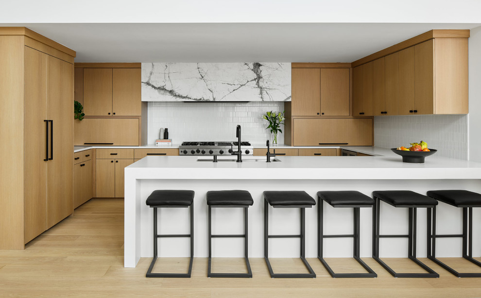 Example of a trendy u-shaped open concept kitchen design in Chicago with flat-panel cabinets, white backsplash, mosaic tile backsplash, stainless steel appliances, a peninsula and white countertops