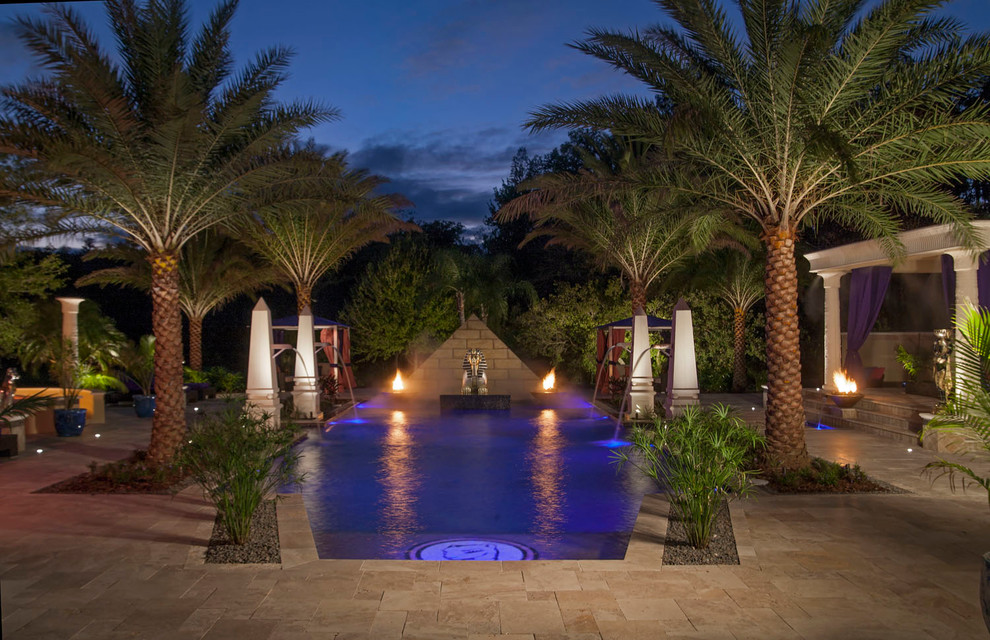 Inspiration for a large mediterranean backyard custom-shaped pool in Tampa with a water feature and natural stone pavers.