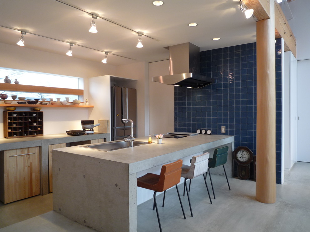 Asian galley kitchen in Other with a drop-in sink, flat-panel cabinets, light wood cabinets, concrete benchtops, stainless steel appliances, concrete floors, a peninsula, grey floor and grey benchtop.