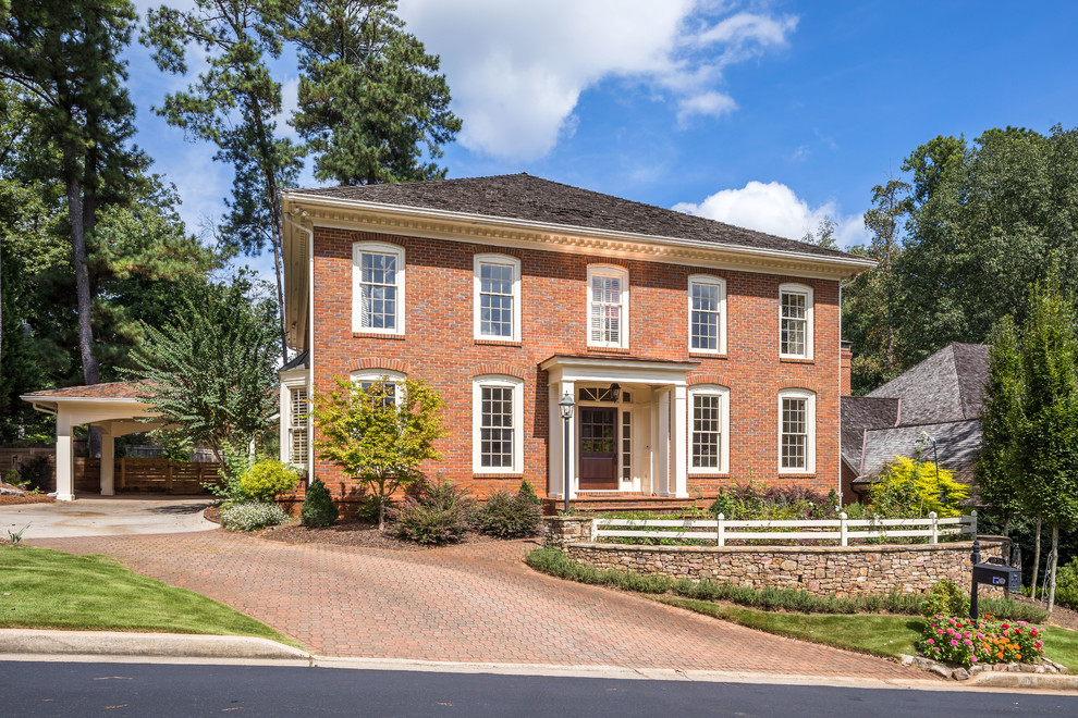 Photo of a traditional two-storey brick red house exterior in Atlanta with a hip roof and a shingle roof.