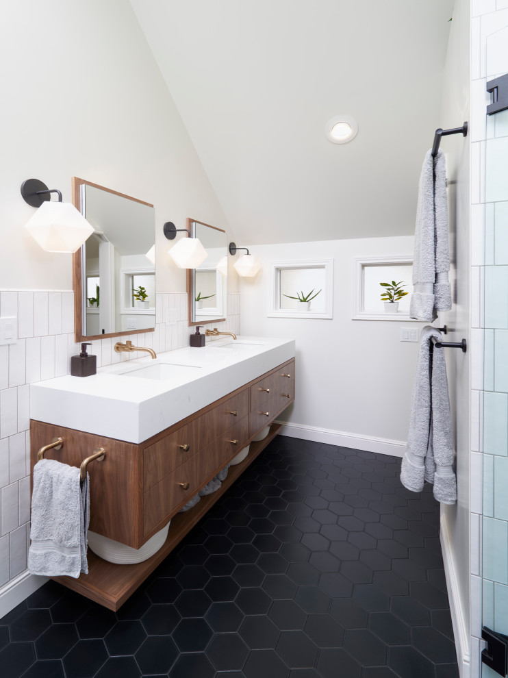 This is an example of a mid-sized transitional master bathroom in Portland with flat-panel cabinets, brown cabinets, a curbless shower, a wall-mount toilet, white tile, ceramic tile, white walls, porcelain floors, an undermount sink, engineered quartz benchtops, black floor, a hinged shower door, white benchtops, an enclosed toilet, a double vanity, a floating vanity and vaulted.