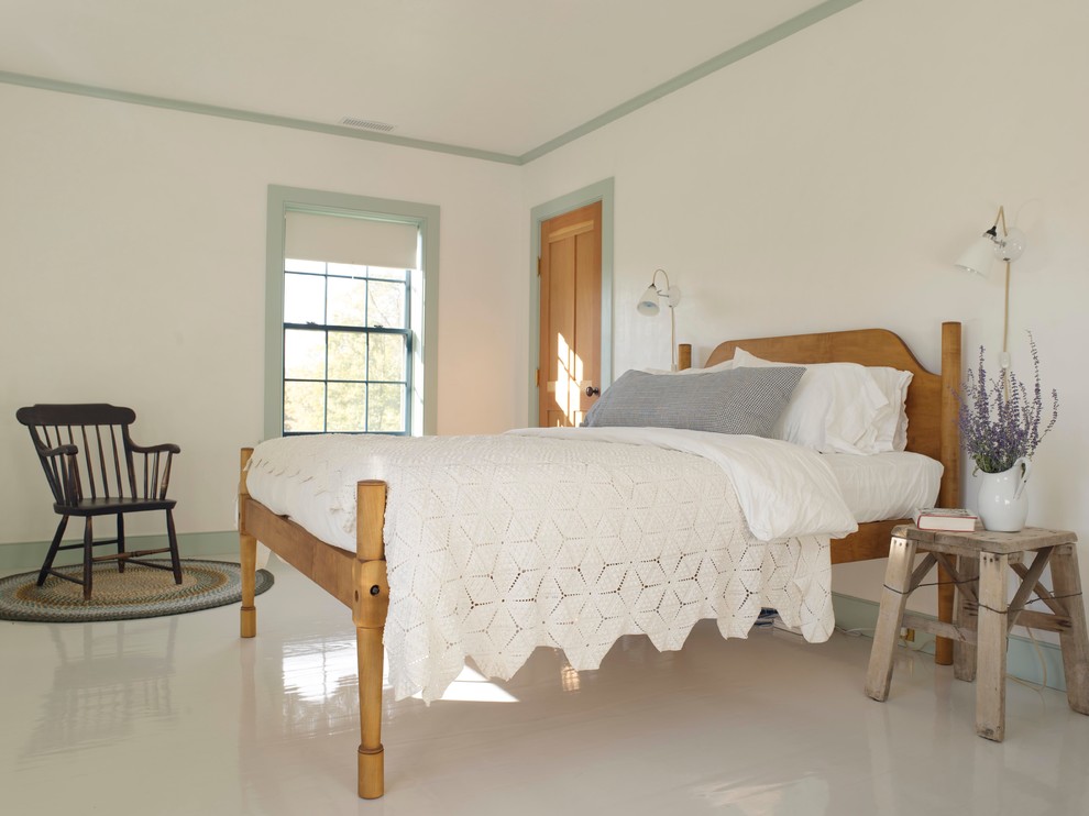 Photo of a country bedroom in New York with white walls, painted wood floors and white floor.