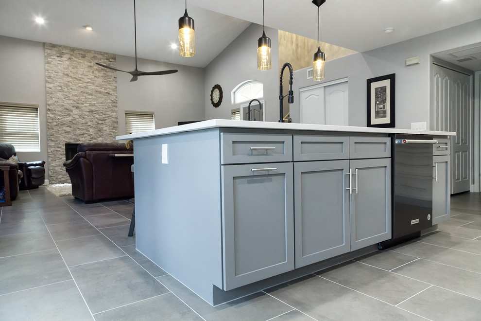 Example of a mid-sized transitional l-shaped porcelain tile and gray floor open concept kitchen design in Phoenix with an undermount sink, shaker cabinets, white cabinets, quartz countertops, gray backsplash, glass tile backsplash, black appliances, an island and gray countertops