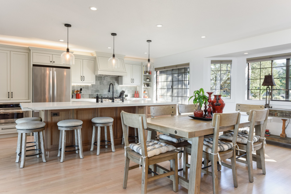 Inspiration for a transitional galley medium tone wood floor and brown floor eat-in kitchen remodel in San Francisco with an undermount sink, shaker cabinets, white cabinets, quartz countertops, gray backsplash, stainless steel appliances, an island and white countertops