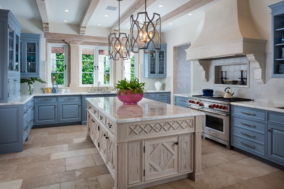 Inspiration for a mediterranean u-shaped kitchen in Miami with an undermount sink, raised-panel cabinets, blue cabinets, stainless steel appliances, with island, beige floor and white benchtop.