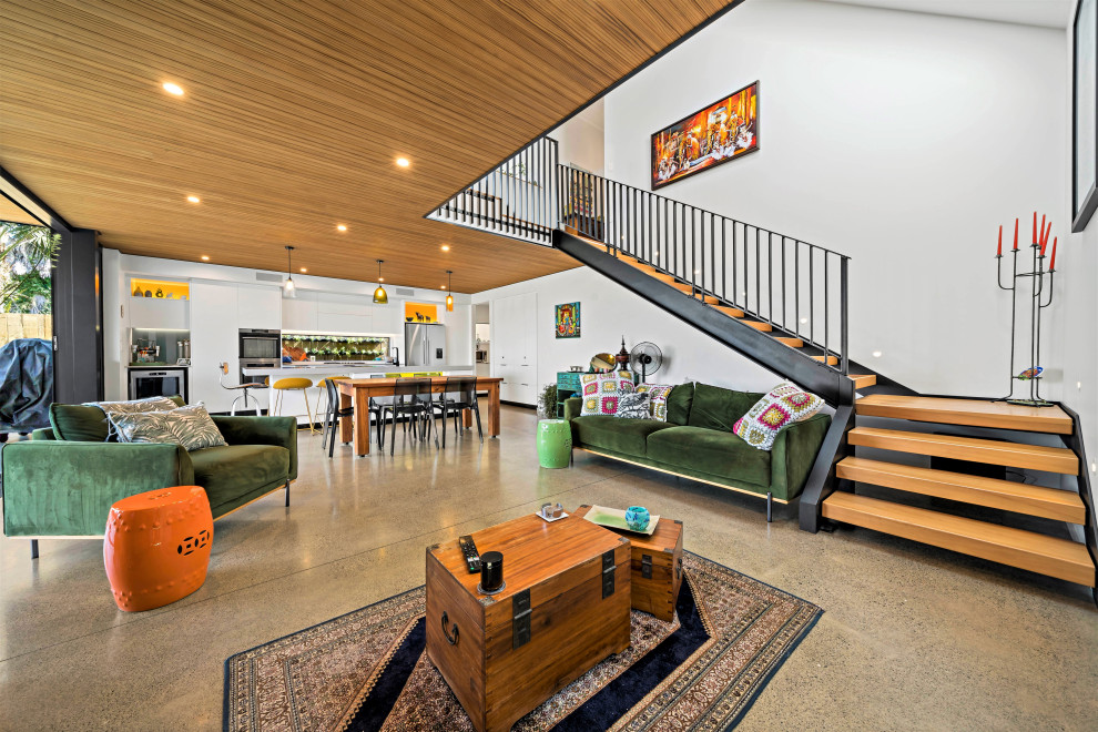 Photo of a large living room in Auckland with white walls, concrete flooring, grey floors and a timber clad ceiling.