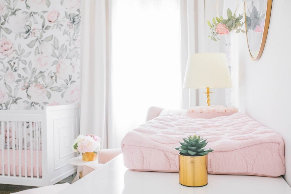 This is an example of a mid-sized transitional nursery for girls in Los Angeles with pink walls, light hardwood floors and brown floor.
