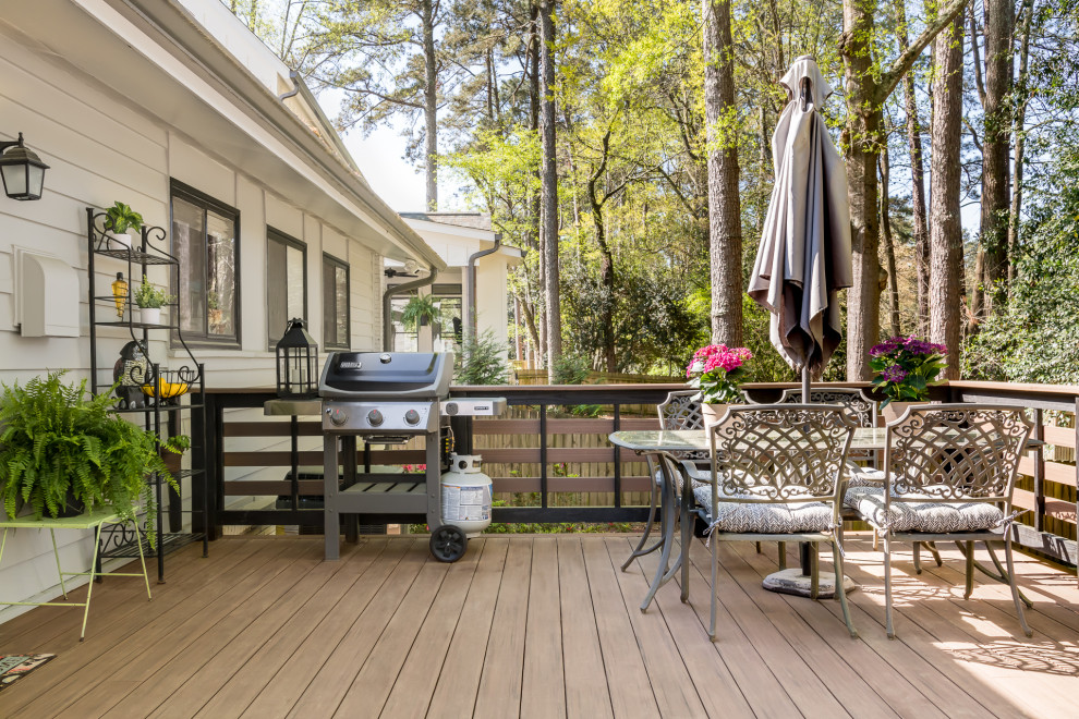 This is an example of a mid-sized modern backyard and ground level deck in Atlanta with no cover and wood railing.