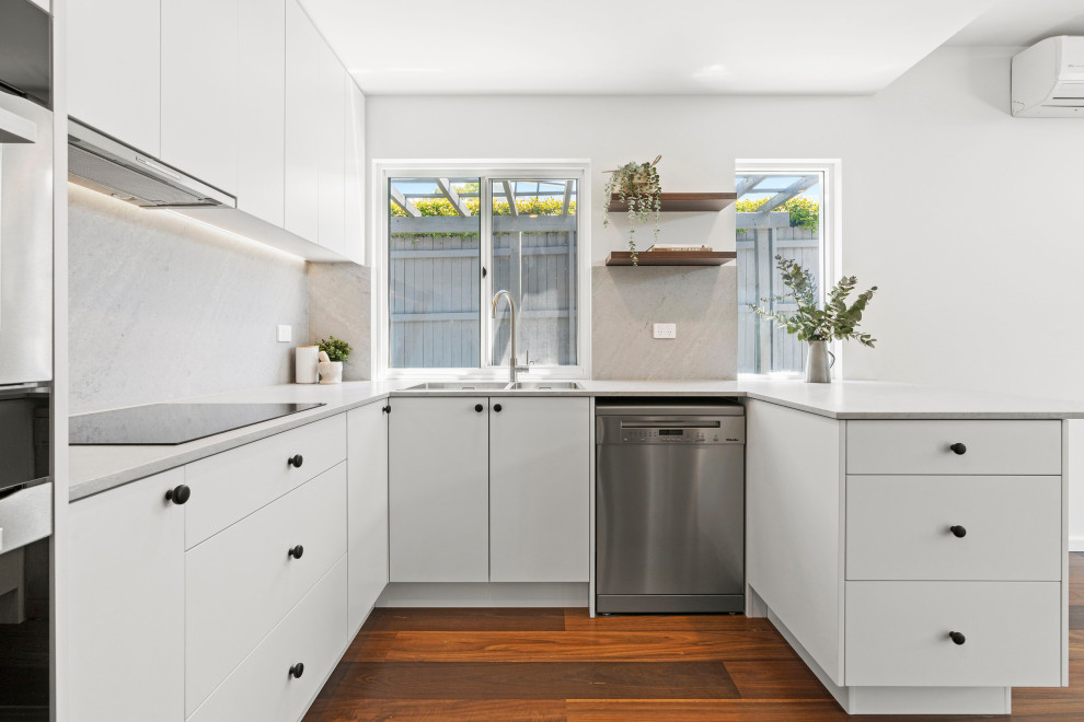 Design ideas for a small u-shaped separate kitchen in Sydney with a double-bowl sink, white cabinets, quartz benchtops, grey splashback, engineered quartz splashback, stainless steel appliances, dark hardwood floors, no island, brown floor and grey benchtop.
