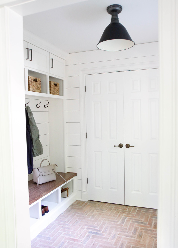 Design ideas for a country mudroom in Chicago with white walls and brick floors.