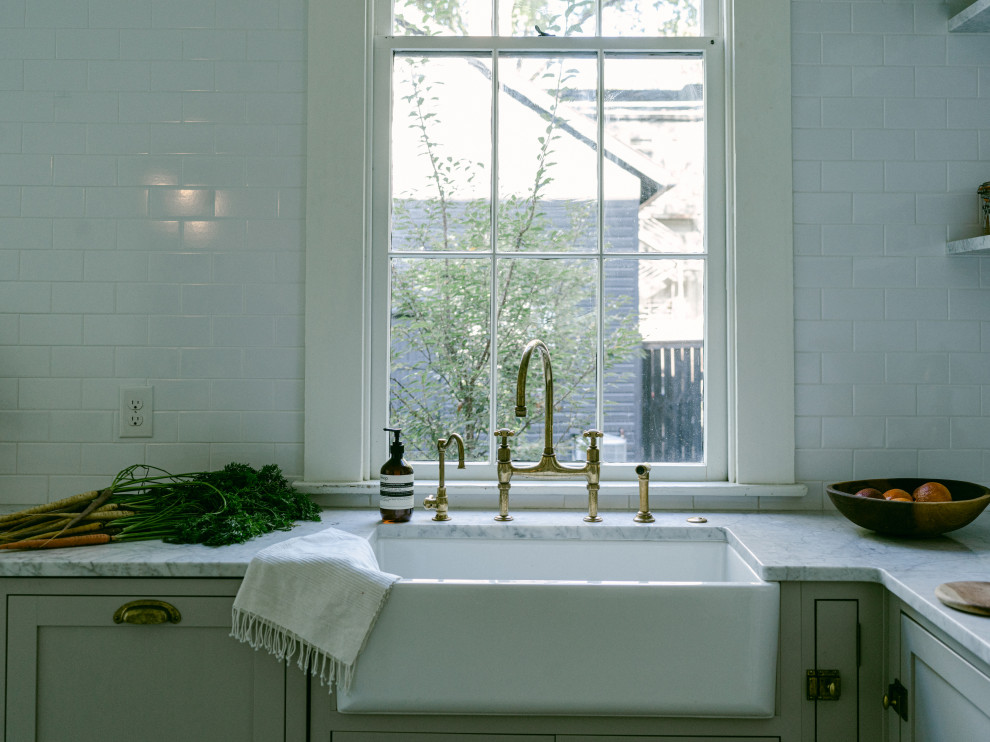 Idéer för mellanstora vintage grått kök, med en rustik diskho, skåp i shakerstil, grå skåp, marmorbänkskiva, vitt stänkskydd, stänkskydd i keramik, svarta vitvaror, marmorgolv, en köksö och vitt golv