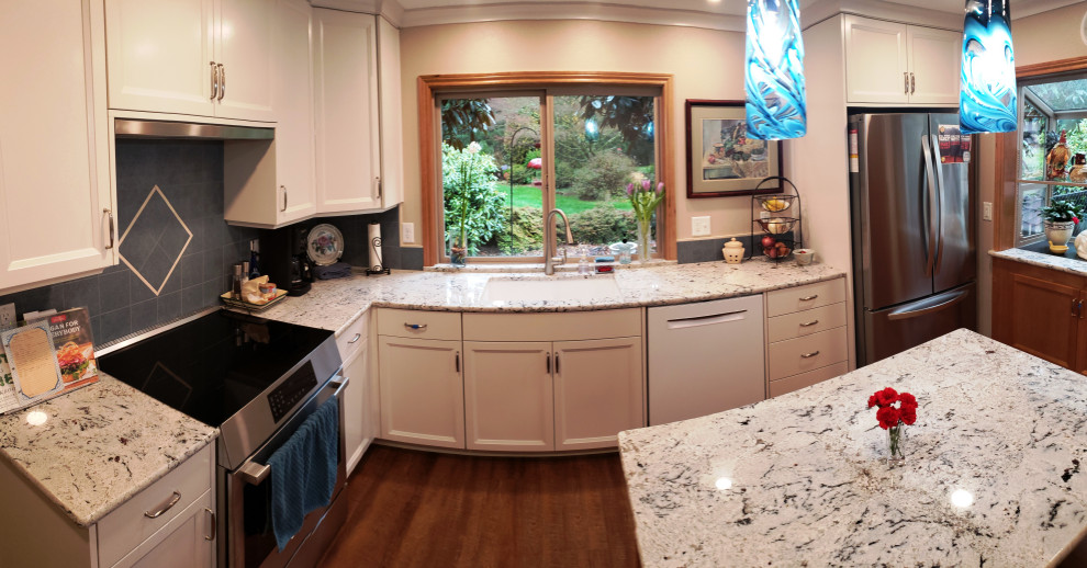 This is an example of a mid-sized traditional l-shaped separate kitchen in Portland with an undermount sink, shaker cabinets, white cabinets, granite benchtops, blue splashback, porcelain splashback, stainless steel appliances, vinyl floors, with island, brown floor and white benchtop.