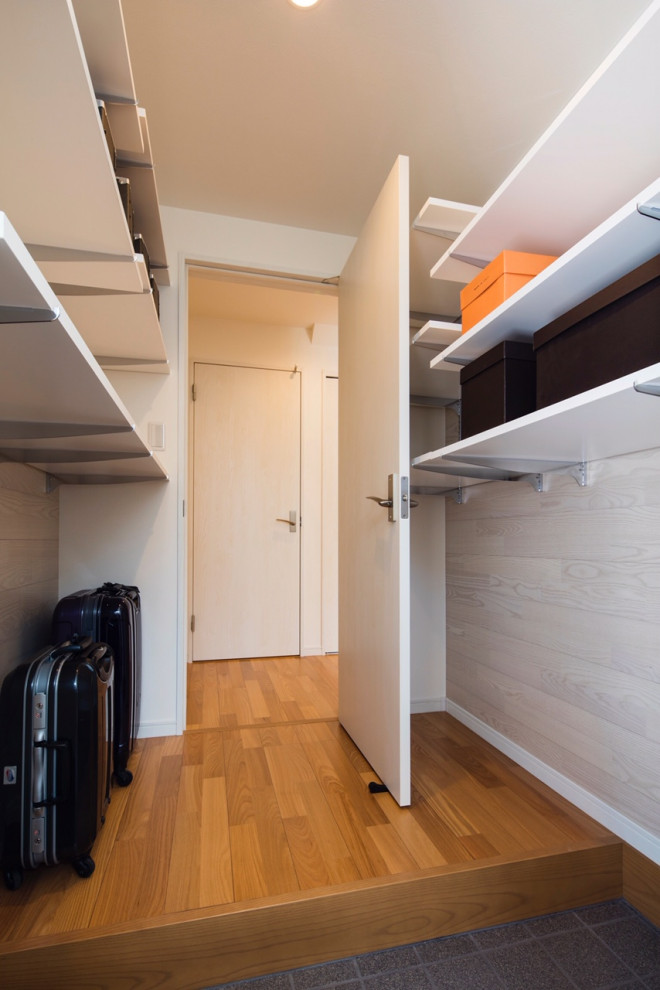 Design ideas for a mid-sized modern gender-neutral walk-in wardrobe in Tokyo with open cabinets, light hardwood floors, beige floor and wallpaper.