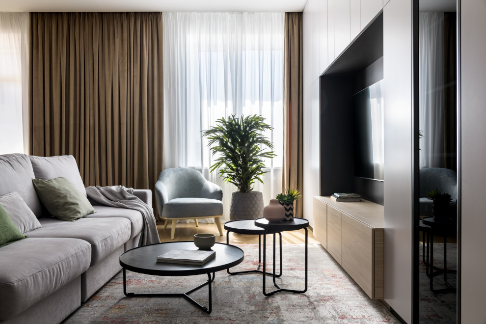 Идея дизайна: открытая, объединенная, серо-белая гостиная комната среднего размера:: освещение в современном стиле с с книжными шкафами и полками, серыми стенами, пробковым полом и телевизором на стене