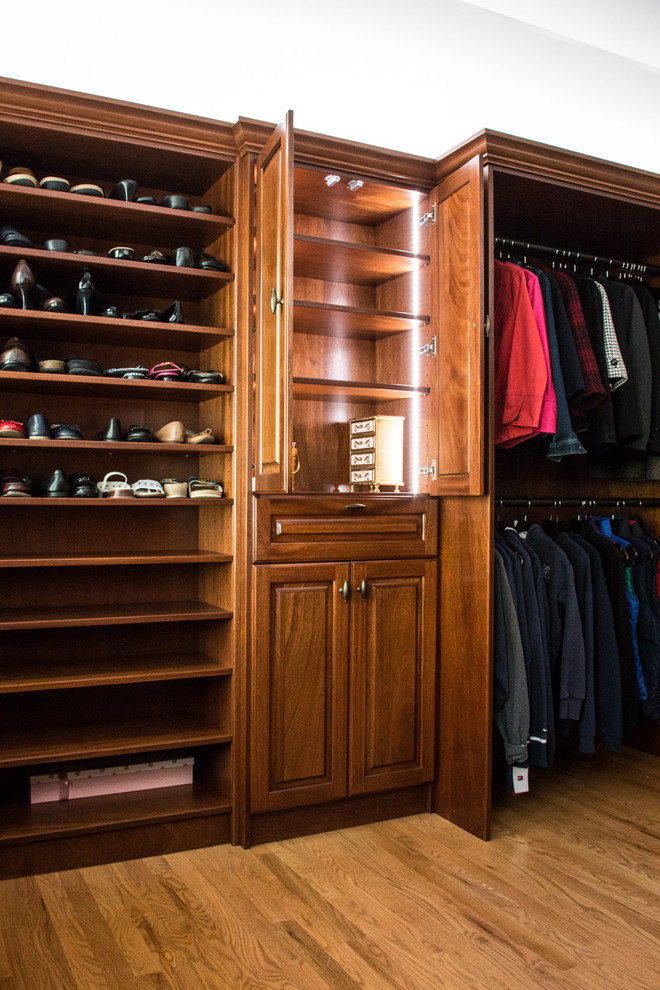 Mid-sized eclectic women's walk-in wardrobe in Philadelphia with recessed-panel cabinets, dark wood cabinets, medium hardwood floors and brown floor.